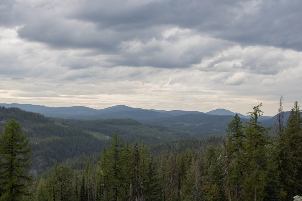 Mountain landscape along Highway 3B en route Rossland with winding roads, dense forest, and distant alpine peaks.