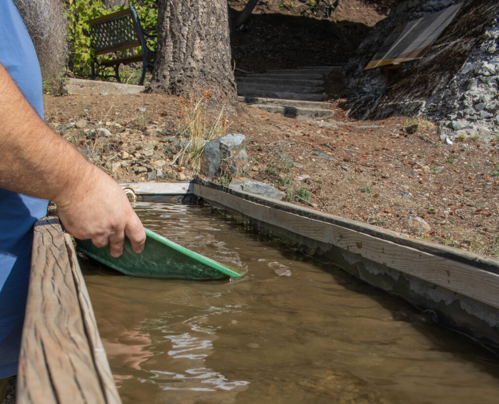 Visitor gold panning at the Rossland Museum & Discovery Centre, exploring BC’s gold rush history in an interactive outdoor exhibit.